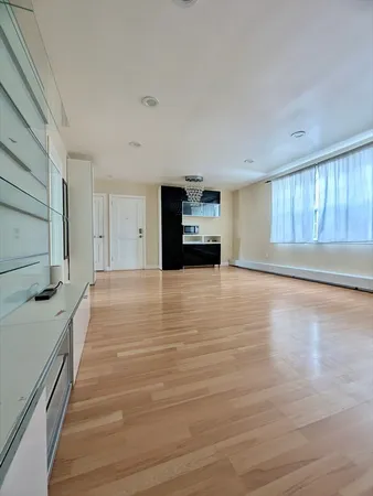 a view of a living room with kitchen island stainless steel appliances wooden floor and window