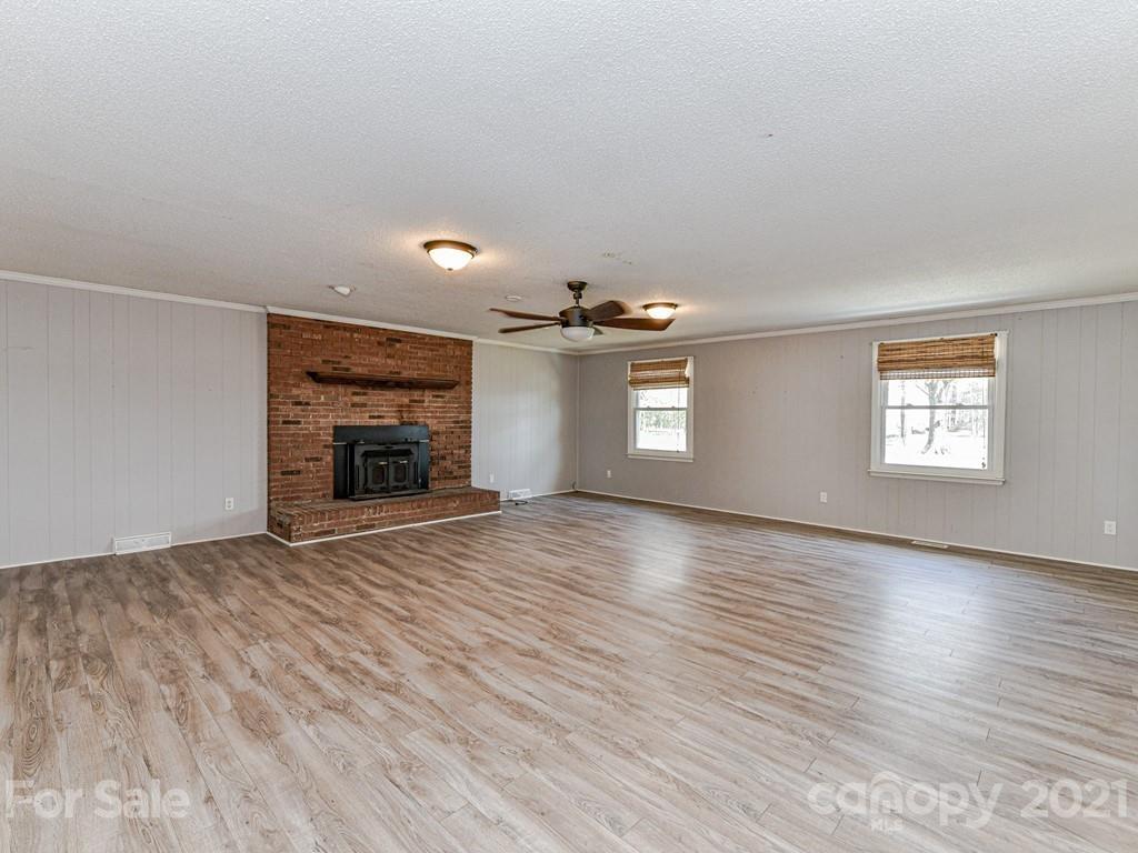 515 Sikes Mill Road Monroe, NC 28110 - Photo 15 of 33 an empty room with wooden floor fireplace and windows