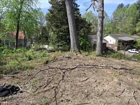 a view of a dry yard with trees and barn in the background