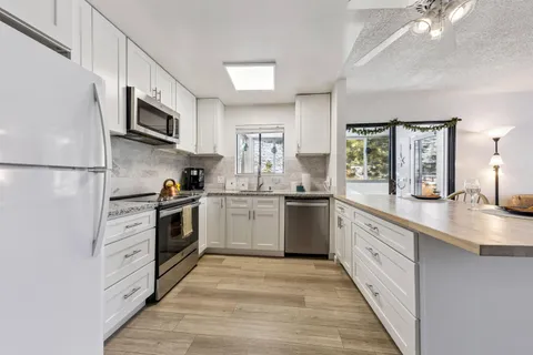 a kitchen with stainless steel appliances a sink cabinets and a window