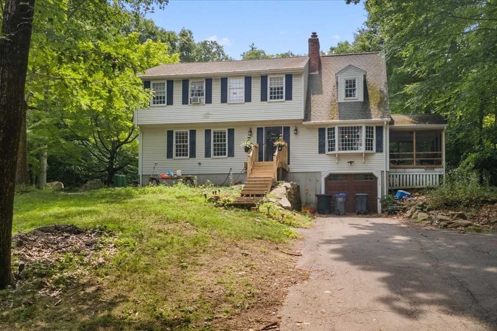 a front view of house with yard and trees in the background