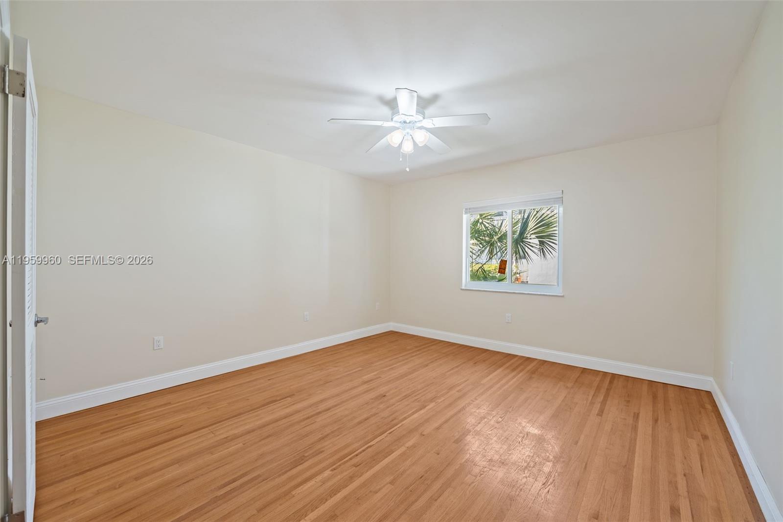 1082 92nd Street, Unit 2 Bay Harbor Islands, FL 33154 - Photo 11 of 19 an empty room with wooden floor chandelier fan and windows
