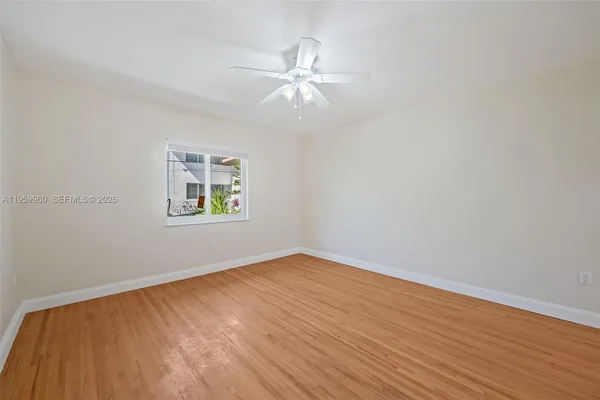 an empty room with wooden floor a ceiling fan and windows