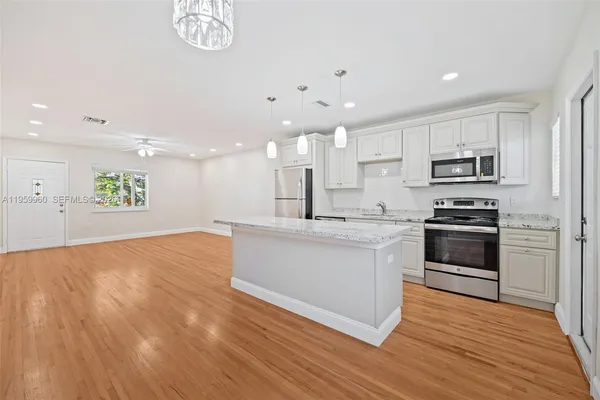 a large kitchen with stainless steel appliances granite countertop a stove a sink and a microwave