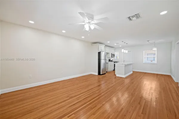a view of an empty room with a window and wooden floor