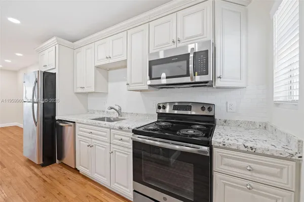 a kitchen with stainless steel appliances granite countertop white cabinets granite counter tops and a stove top oven