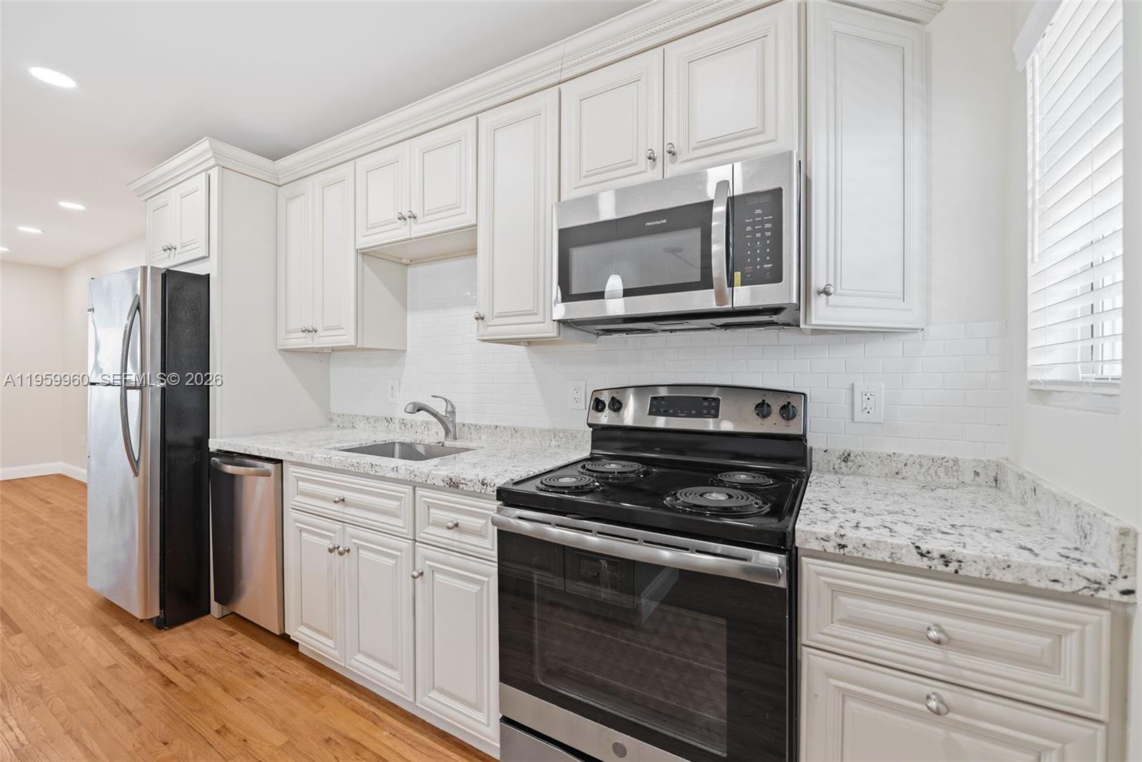 1082 92nd Street, Unit 2 Bay Harbor Islands, FL 33154 - Photo 8 of 19 a kitchen with stainless steel appliances granite countertop white cabinets granite counter tops and a stove top oven