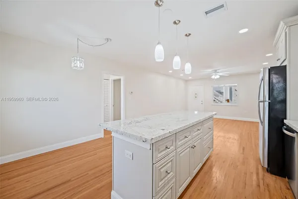 a kitchen with white cabinets and wooden floor