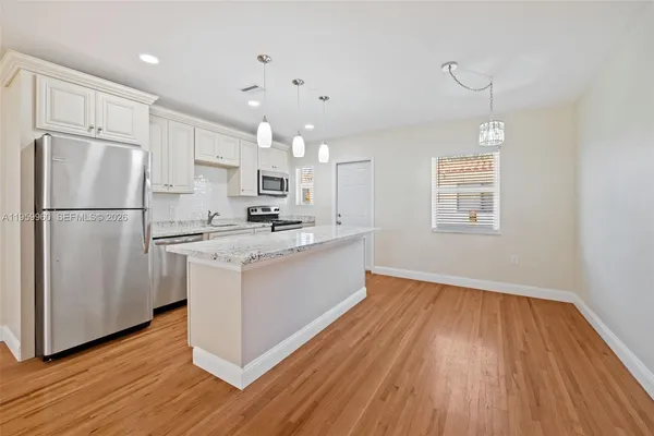 a kitchen with kitchen island white cabinets and wooden floor