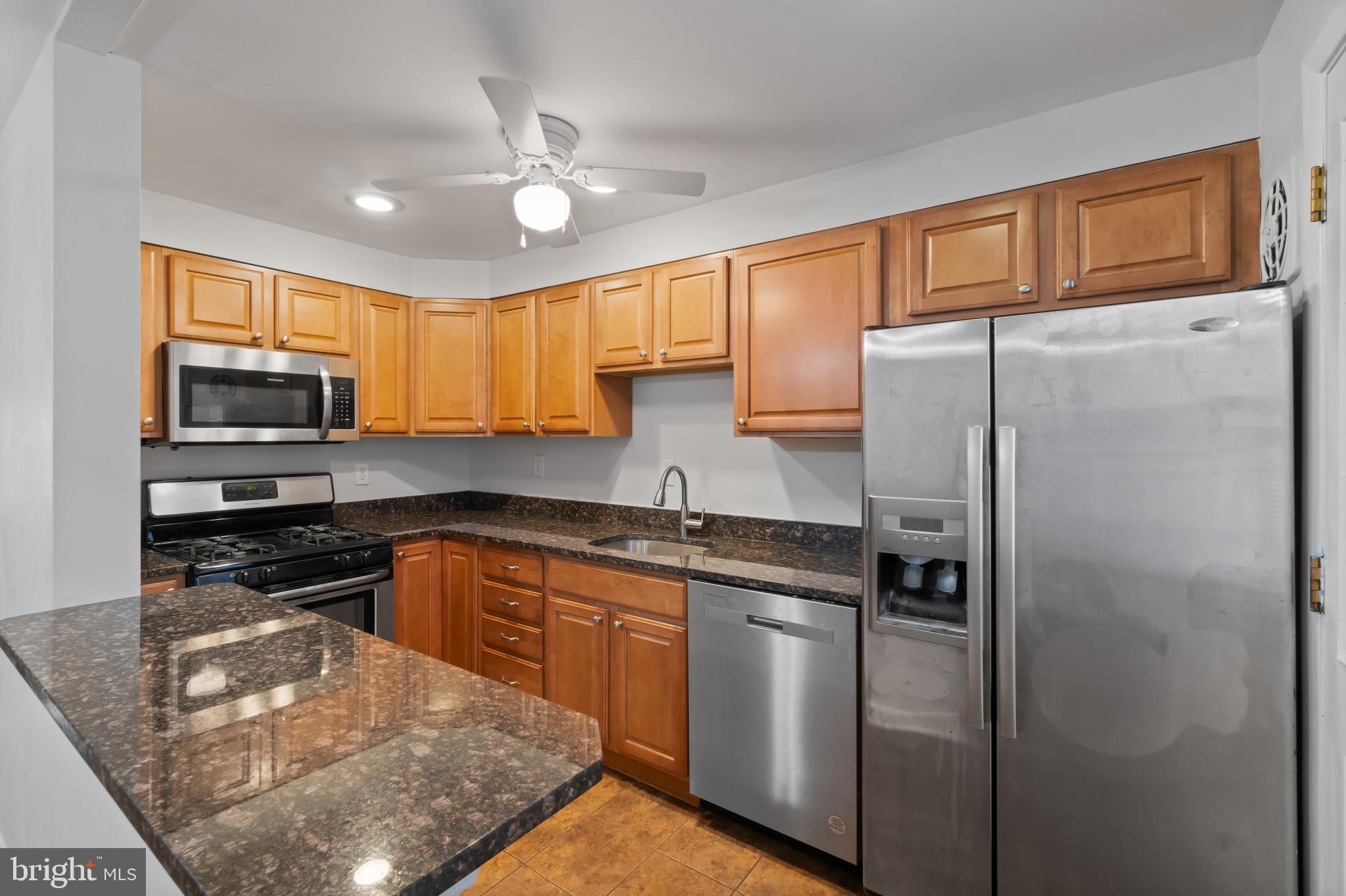8146 Del Haven Road Baltimore, MD 21222 - Photo 9 of 35 a kitchen with stainless steel appliances granite countertop a refrigerator a sink dishwasher a stove top oven a kitchen island and chairs with wooden floor