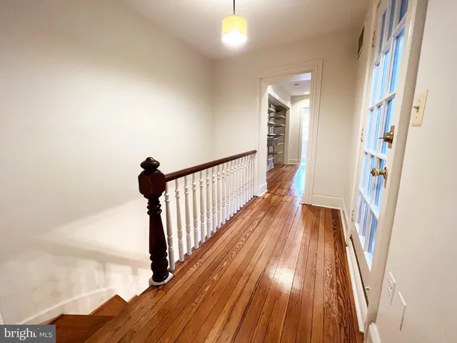 a view of a hallway with wooden floor and staircase