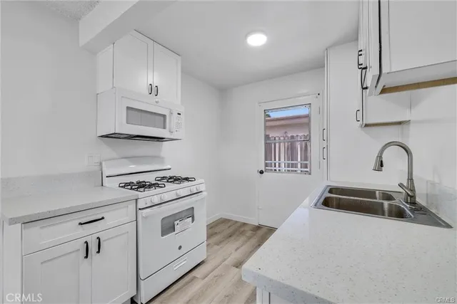 a kitchen with white cabinets a sink and appliances