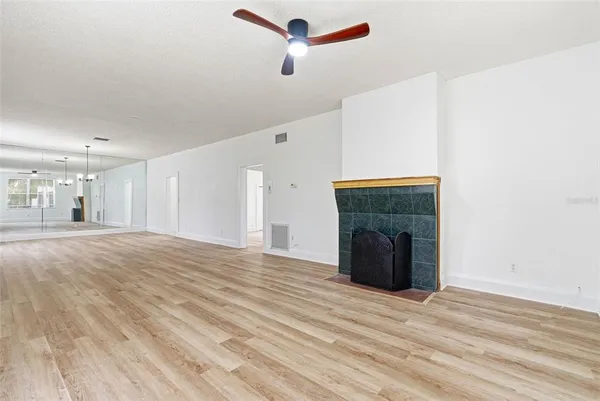 a view of an empty room with wooden floor and a fireplace