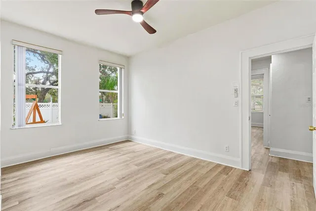 an empty room with wooden floor cabinet and ceiling fan