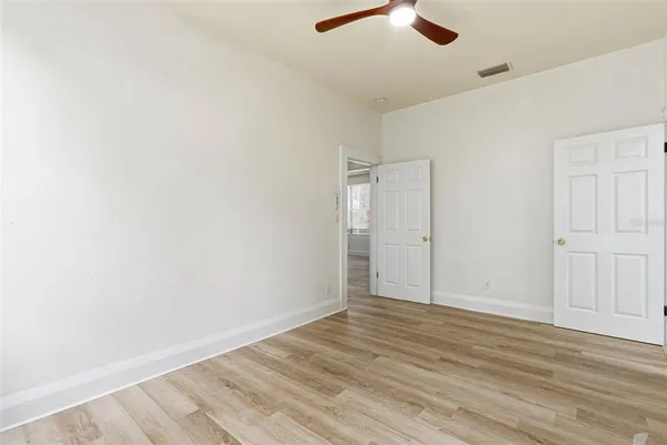 an empty room with wooden floor cabinet and ceiling fan