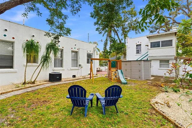 a view of a backyard with table and chairs and a large tree
