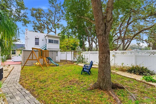 a view of a backyard with table and chairs and a large tree