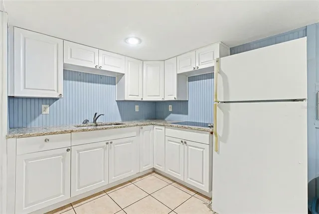 a kitchen with granite countertop white cabinets and a sink