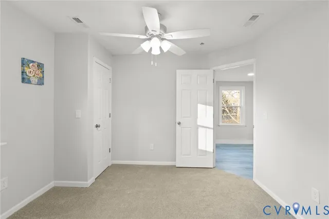 an empty room with windows and fan