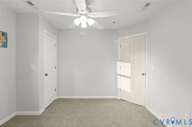 an empty room with a chandelier fan and closet area