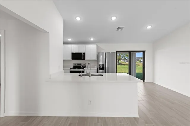 a view of kitchen with sink microwave and refrigerator