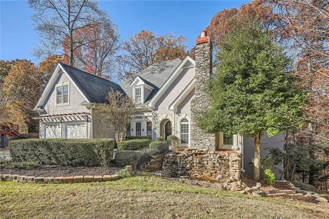 a view of a white house next to a yard with plants and trees