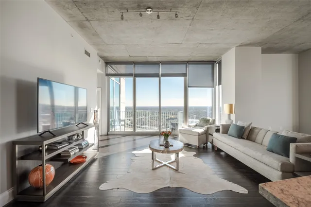 a living room with furniture a large window and wooden floor