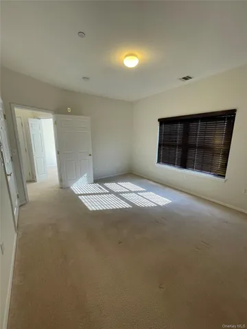 a view of an empty room with wooden floor and closet
