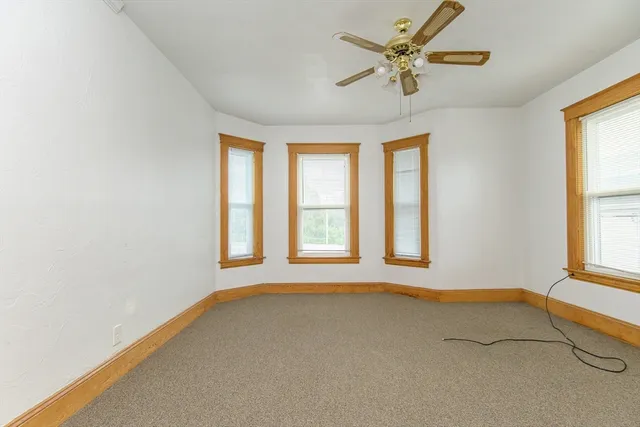 an empty room with windows and fan