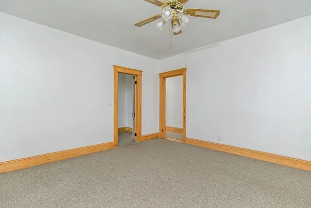 an empty room with a chandelier fan and windows