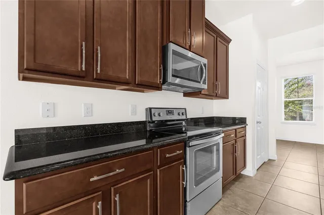 a kitchen with stainless steel appliances granite countertop white cabinets stove and microwave