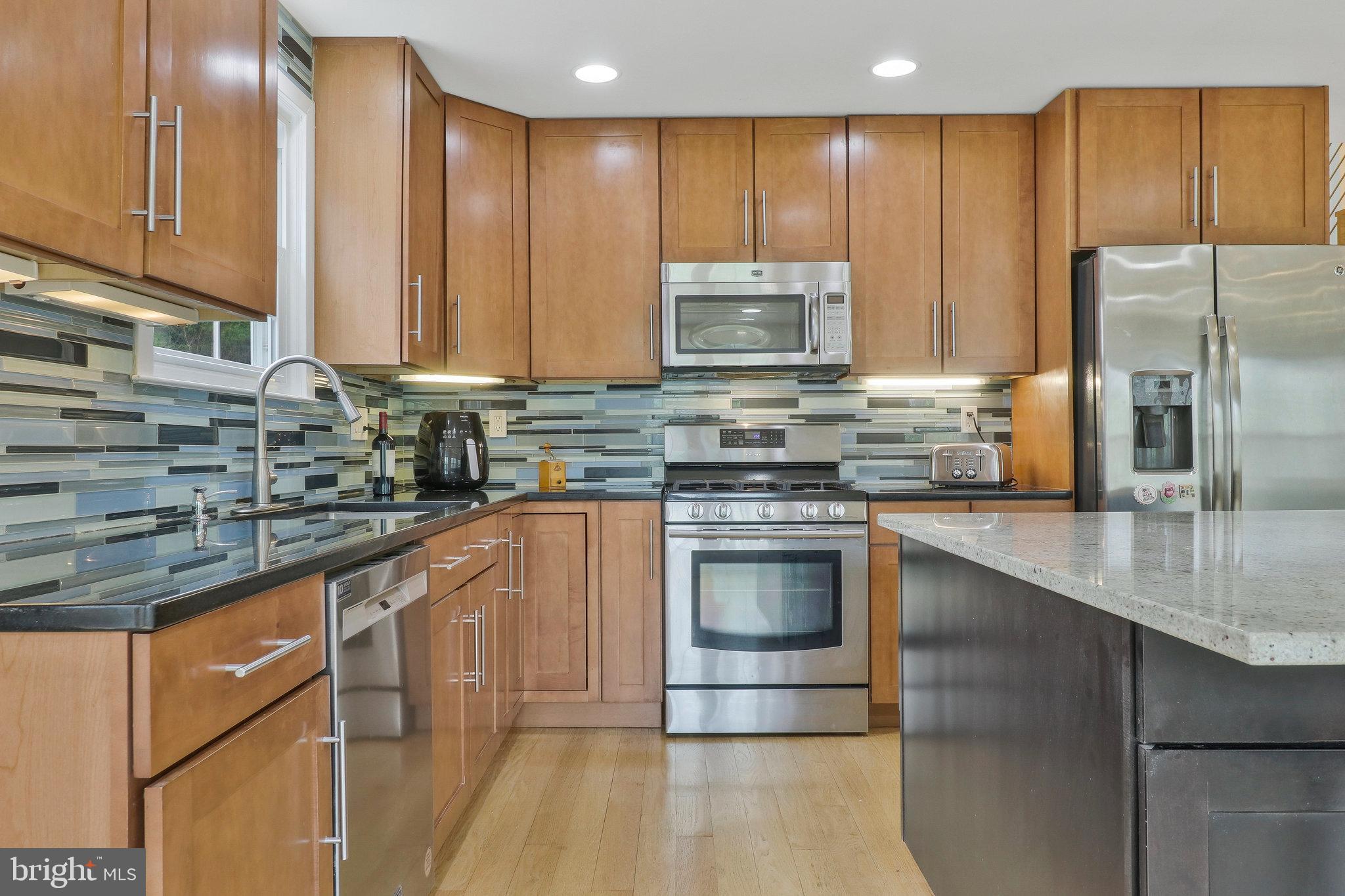 8543 Howell Road Bethesda, MD 20817 - Photo 8 of 24 a kitchen with stainless steel appliances granite countertop a sink a stove and a refrigerator
