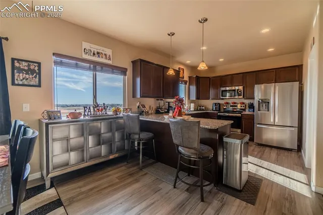 a kitchen with stainless steel appliances kitchen island granite countertop a refrigerator a stove top oven a sink with island and chairs