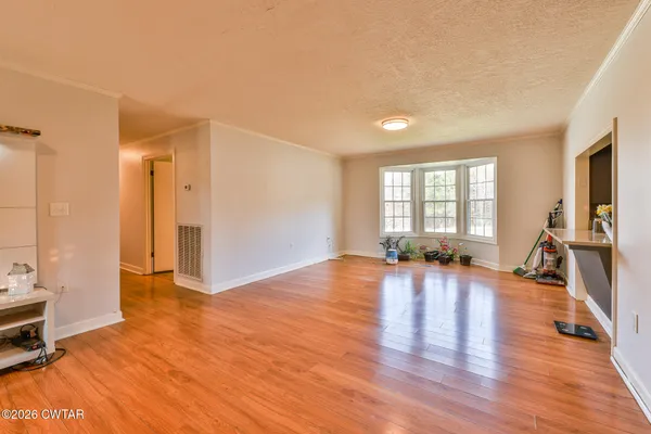 a view of empty room with wooden floor and windows