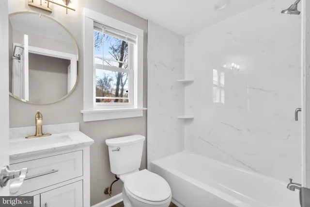 a bathroom with a toilet sink vanity tub and mirror