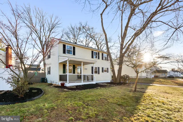 a view of a white house with a large tree in front of it
