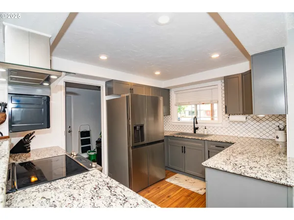 a kitchen with stainless steel appliances kitchen island granite countertop a sink refrigerator and cabinets