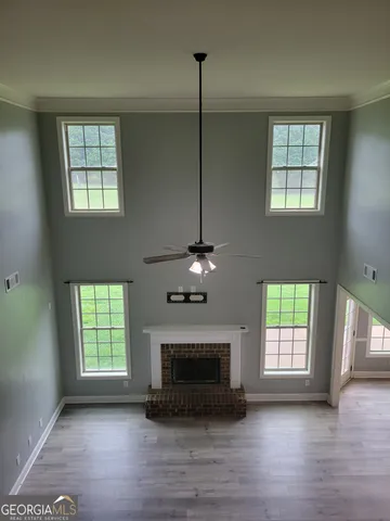 a view of an empty room with wooden floor fireplace and a window
