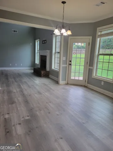 an empty room with fireplace chandelier and windows