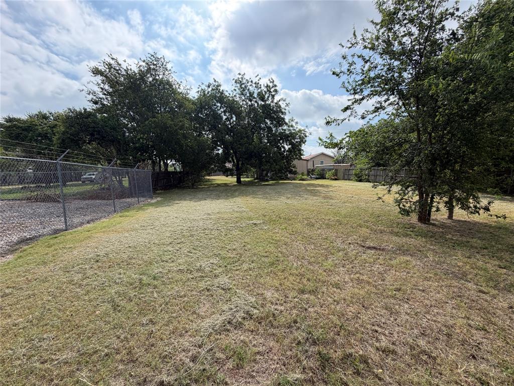 267 North Katy Road Elm Mott, TX 76640 - Photo 20 of 21 Expansive grassy lot featuring mature trees and a chain-link fence
