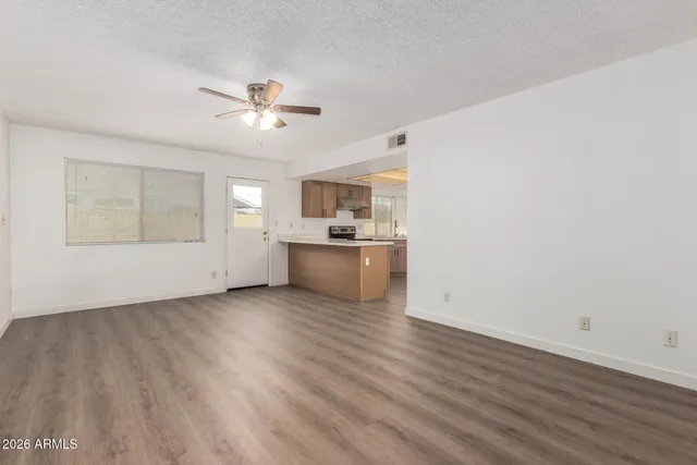 an empty room with wooden floor and windows