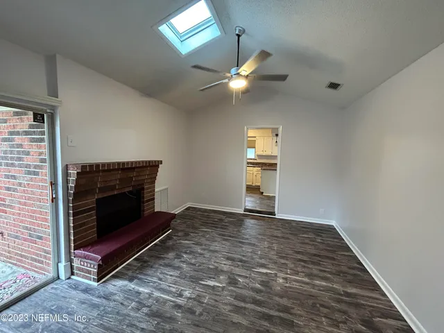 an empty room with windows fireplace and fan
