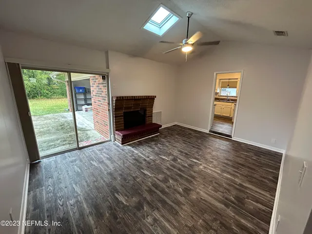 an empty room with wooden floor fan and windows