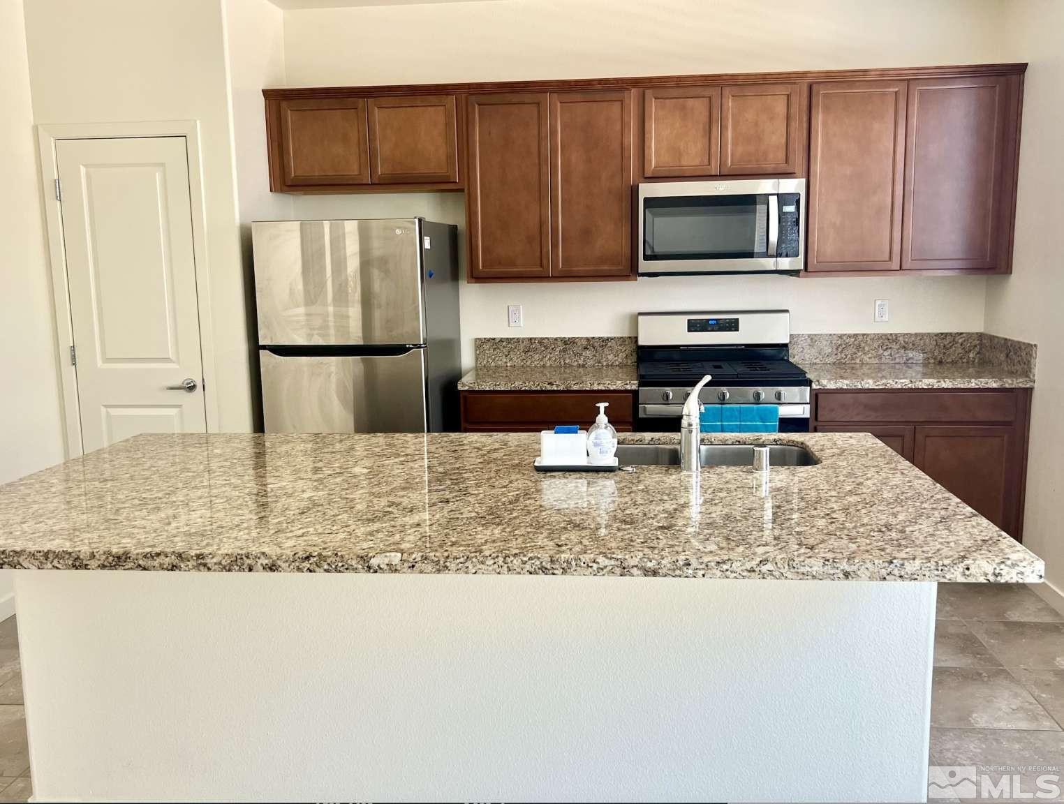 4880 Little Rock Way Sun Valley, NV 89433 - Photo 8 of 30 a kitchen with stainless steel appliances granite countertop a refrigerator sink stove microwave and stove