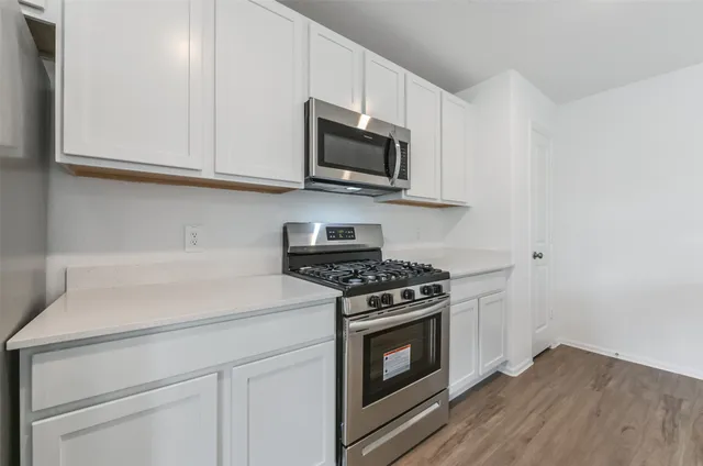 a kitchen with stainless steel appliances white cabinets and a stove top oven