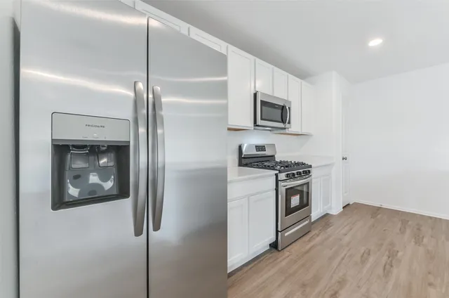 a kitchen with stainless steel appliances kitchen island granite countertop a refrigerator and a stove top oven