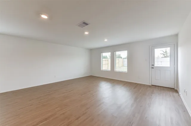 a kitchen with stainless steel appliances kitchen island granite countertop a stove a sink a refrigerator and white cabinets with wooden floor