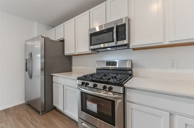 a kitchen with stainless steel appliances white cabinets and a stove top oven