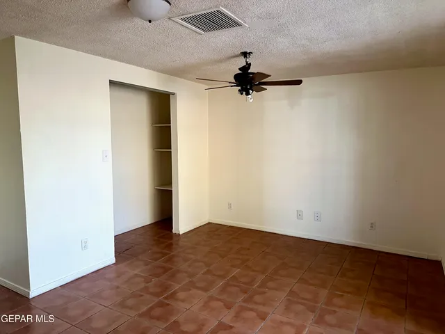an empty room with a ceiling fan and carpet
