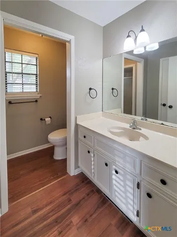 a spacious bathroom with a double vanity sink a toilet and a large mirror